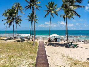 塔曼达雷Flat Beira Mar - Carneiros Beach Resort的棕榈树和海洋海滩上的木板路