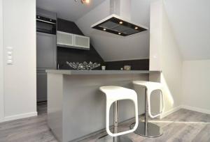 卑尔根Modern apartment 7 min to center的厨房在柜台上配有两个白色凳子