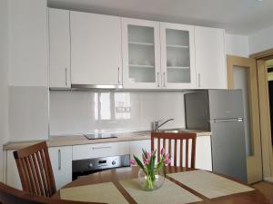 普洛切Apartman Roko的厨房配有白色橱柜和桌椅