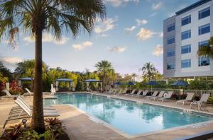 奥兰多The Celeste Hotel, Orlando, a Tribute Portfolio Hotel的一座带椅子和棕榈树的游泳池以及一座建筑