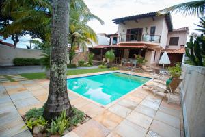 尼泰罗伊Casa a 50m da Praia de Itacoatiara Niteroi RJ的棕榈树旁带游泳池的房子