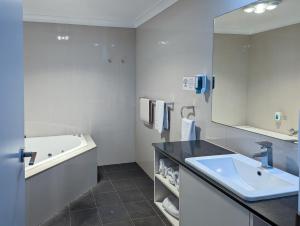 芒特甘比尔阿卡纳汽车旅馆及阳台公寓的一间带水槽、浴缸和镜子的浴室