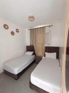 达赫拉Mini villa dakhla的白色墙壁客房的两张床
