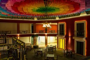 乔卢拉Hotel Casa Real Cholula的大房间设有桌子和色彩缤纷的天花板