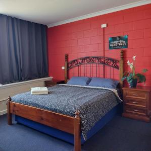 阿德莱德阿德莱德港背包客旅舍的一间卧室配有一张红墙木床