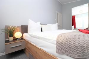NeuhausMeerquartier App 08的卧室配有白色大床和灯