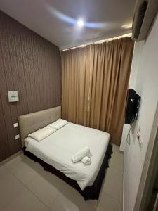 古晋One Point Hotel @ Airport (Kuching)的带电视的小客房内的小床