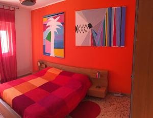 巴勒莫B&B La Galleria的一间卧室配有一张带橙色墙壁和彩色画作的床。