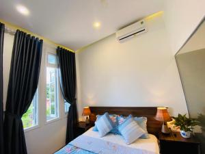 Thôn Kim Long (1)Mia's House Hue的卧室配有带枕头的床铺和窗户。