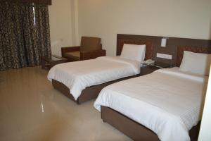 KatraHotel Sravasti Residency的酒店客房,配有两张床和椅子