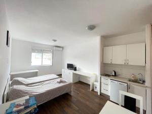 莫斯塔尔City Apartments的一间白色的小房间,配有床和厨房