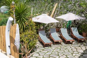 波西塔诺Casa Romelide Positano Amazing view, free parking along the street, free breakfast basket的庭院里摆放着一组椅子和遮阳伞