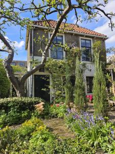 豪达Apple Tree Cottage - discover this charming home at beautiful canal in our idyllic garden的前面有花园的房子