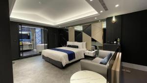竹北H Motel玺悦国际精品旅馆的一间卧室配有一张床、一张沙发和一把椅子