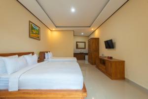 勒吉安Liliy Guest House Kuta - Badung的卧室配有一张白色大床和电视。