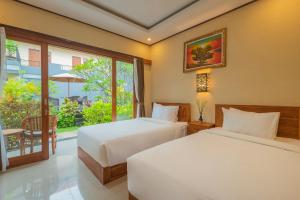 勒吉安Liliy Guest House Kuta - Badung的配有窗户的酒店客房内的两张床
