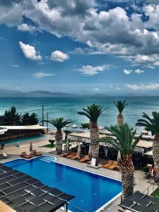 波利蒂卡Evvoiki Akti Hotel的棕榈树和大海的游泳池