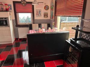 因弗内斯Gleninver Guest House的厨房铺有红色和黑色的地板,配有桌子