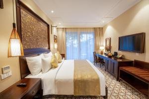 会安Ahoy Hoi An Boutique Resort & Spa的酒店客房配有一张床、一张书桌和一台电视。