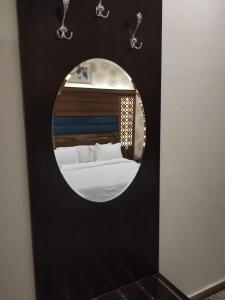 海米斯穆谢特امارلس للشقق الفندقية的黑色墙上的圆镜子,带床