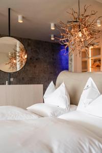 思科纳Hotel Mitterplatt (Schenna Resort)的一间卧室配有两张带白色床单和吊灯的床。