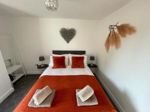 斯蒂夫尼奇Luxury One Bed Apartment Stevenage的卧室配有带橙色枕头的床,墙上有心