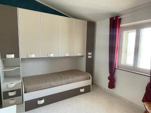 拉契亚Dimora Pina sul mare的一间卧室配有一张床、橱柜和窗户。