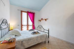 奇亚Villa Leonardo Sud Sardegna的一间卧室配有床和一个带粉红色窗帘的窗户。