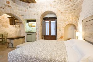 阿尔贝罗贝洛Trulli Holiday Albergo Diffuso的卧室配有一张石墙内的大床