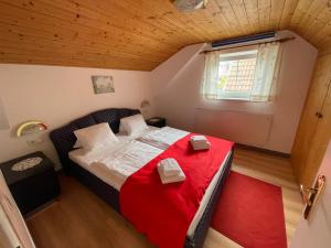 博登斯多夫兰德莫妮卡公寓的一间小卧室,配有一张带红色毯子的床
