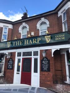 伊普斯威奇The Harp Freehouse and Guesthouse的一座砖砌的建筑,上面有读竖琴的标志