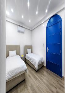 MukāwirLara Family Resorts的蓝色门的客房内的两张床