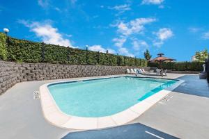 韦瑟福德速8威德福汽车旅馆的一座拥有石墙和蓝天的游泳池