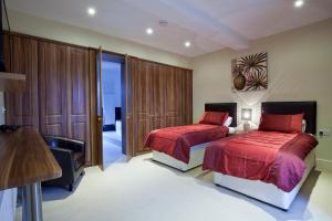 滨海凯斯特Premier Apartments的一间卧室配有两张带红色床单和椅子的床