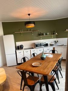 莱萨布勒-多洛讷La Maison des sables , 300m de la plage的一间带木桌和椅子的厨房以及一间配有冰箱的厨房