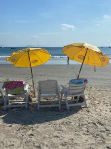 加罗帕巴Pousada Maré Mar的海滩上的两把椅子和两把遮阳伞