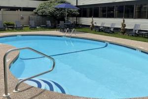 纳舒厄Clarion Inn的一个带椅子和遮阳伞的大型蓝色游泳池