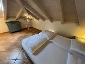 托尔博莱Mansarda Baia Azzurra 8的一间带一张白色大床的卧室,位于带木制天花板的房间内