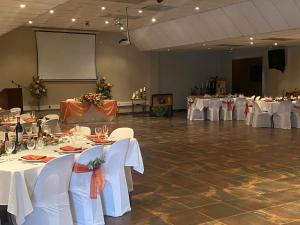 丹地Amabutho Warrior Lodge的一个带白色桌椅的大型宴会厅