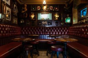 锡豪西斯The Olde Ship Inn的一间酒吧,配有红色皮革座椅和电视