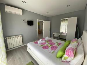 吉尔斯Cantinho Verde T1的一间卧室配有带粉色和绿色枕头的床