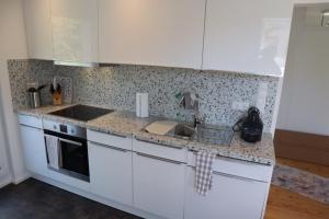 加格瑙Ferienwohnung Habitat的厨房配有白色橱柜、水槽和炉灶。