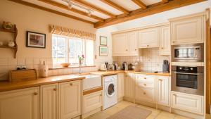 奇平卡姆登Boddingtons Barn @ Norton Grounds的厨房配有白色橱柜、洗衣机和烘干机