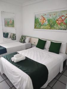 塞古罗港Hotel Porto Verde -JG的客房配有两张带绿色和白色枕头的床。