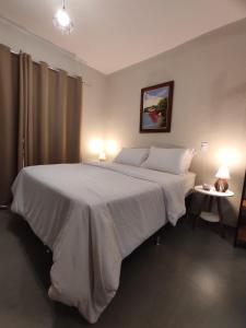 戈亚斯州上帕莱索TEMPO FLATS E HOSPEDAGEM的一间卧室配有一张带两盏灯的大型白色床。