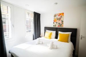 蒂尔Happy 1 Bedroom Apartment的一间卧室配有两张白色床和黄色枕头