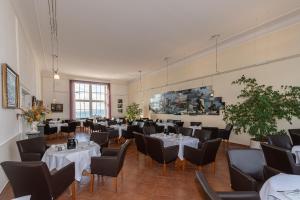 萨斯尼茨萨斯尼茨库恩酒店的用餐室配有白色桌子和黑色椅子
