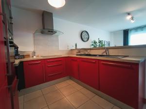 图卢兹T3 Lumineux - Berges de la Garonne - Parking的一间带红色橱柜和水槽的厨房