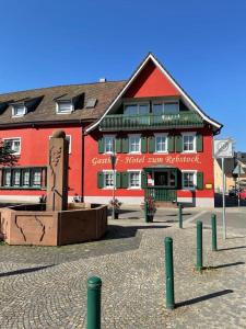 玛特丁恩Gasthof Hotel zum Rebstock的一座红色的建筑,前面有雕像