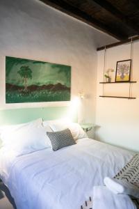 加尔达尔Casa El Terrero的卧室配有一张白色床,墙上挂有绘画作品